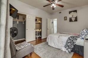 Quarto com cama, mesa de cabeceira, ventilador, armário e ventoinha no teto.