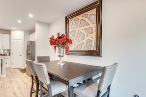 A dining area with a dark wooden table, grey upholstered chairs, and a vase with red flowers. - Work & Play Near Old Hickory Lake! Home w/ Patio (Gallatin)