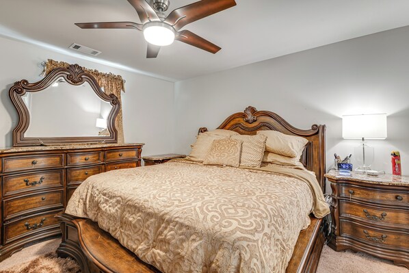 Un dormitorio con una cama grande, cómoda de madera y ventilador de techo.