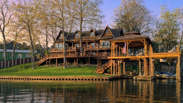 A waterfront property with multiple wooden decks, a flag, and a dock. - 2-tier Dock! Jordan Lake Family Retreat (Titus)