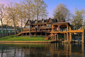 A waterfront property with multiple wooden decks, a flag, and a dock. - 2-tier Dock! Jordan Lake Family Retreat (Titus)