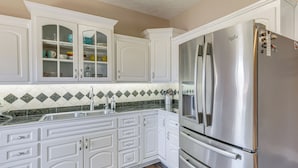 A kitchen with white cabinetry, a stainless steel refrigerator, and a green and white tiled backsplash. - 2-tier Dock! Jordan Lake Family Retreat (Titus)