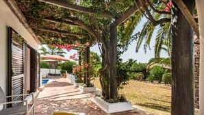 A covered patio with white lounge chairs, a yellow cushion, and a pergola with climbing plants. - Casa Rouxinol in Carvoeiro (Lagoa)