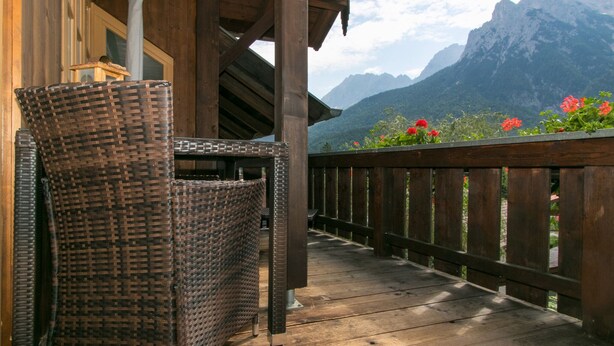 A wicker chair on a wooden deck with a mountain view. - Landhaus Albrecht - Holiday apartment 03 (51 m²) for 2 guests with 2 balconies (Mittenwald)