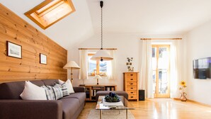 A modern living room with a wooden ceiling, a sofa, a coffee table, and a TV. - Landhaus Albrecht - Holiday apartment 03 (51 m²) for 2 guests with 2 balconies (Mittenwald)