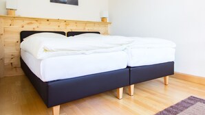 A neatly made bed with white linens, a wooden headboard, and a single lamp on a bedside table. - Landhaus Albrecht - Holiday apartment 03 (51 m²) for 2 guests with 2 balconies (Mittenwald)