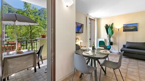A dining area with a table set for two, a sofa, and a TV on the wall. - Mobilehome in Porlezza am Luganersee (Porlezza)