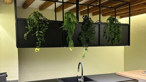 Una cuina moderna amb taulell negre, un sol d'obra integrat i bigues de fusta al sostre.