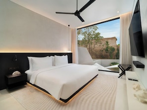 A modern hotel room with a large bed, a ceiling fan, a TV, and a view of the outdoors.