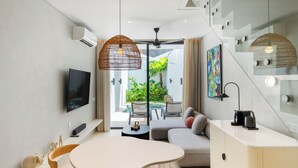 Un salon moderne comprenant un canapé, une table basse, un téléviseur et un coin repas avec des chaises.