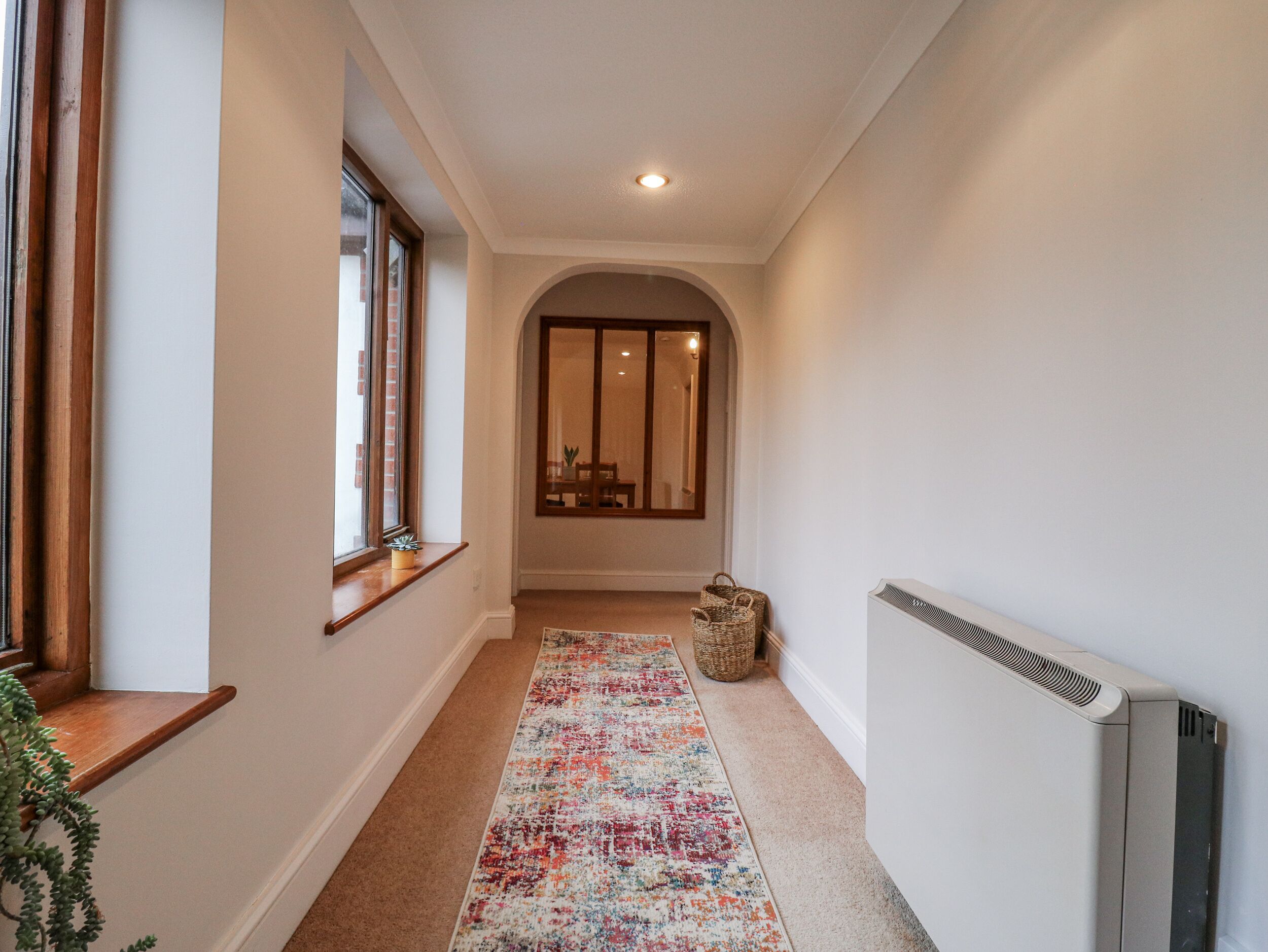 A hallway with a carpet, a radiator, and a window.