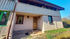 Un edificio de dos pisos con balcón, puerta principal y un pequeño porche.