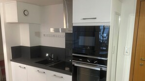 A modern kitchen with white cabinetry, black countertops, stainless steel appliances, and a built-in oven. - Super-central apartment for family or business (Châlons-en-Champagne)