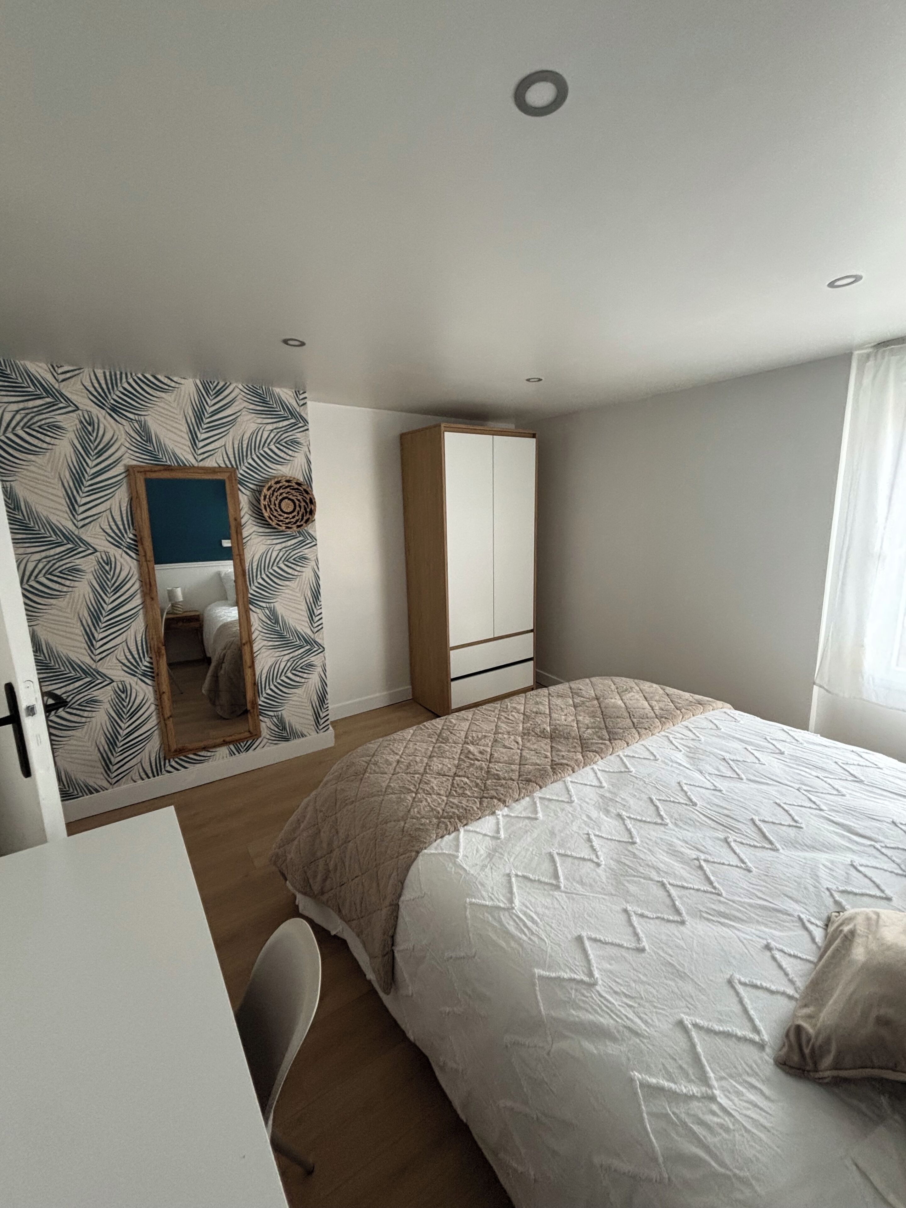 Une chambre à coucher avec un lit, une armoire, un bureau et un miroir.