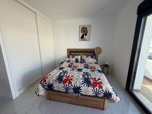 A bedroom with a bed, a wooden headboard, a wall-mounted picture, a small bedside table with a lamp, and a window with a view. - Casa Montgavina, villa in the heart of Vistabella Golf (Entrenaranjos)