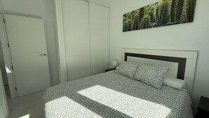 A bedroom with a bed, a nightstand, a wall-mounted painting, and a closed door. - Casa Montgavina, villa in the heart of Vistabella Golf (Entrenaranjos)