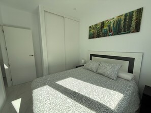 Een slaapkamer met een bed, een nachtkastje, een aan de muur hangend schilderij en een gesloten deur.