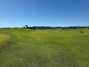 A golf course with a clear sky, green grass, and distant hills. - Casa Montgavina, villa in the heart of Vistabella Golf (Entrenaranjos)
