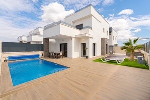 A modern two-story house with a swimming pool, outdoor seating, and a well-maintained lawn.