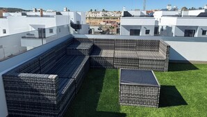 A rooftop terrace with wicker furniture and a small table, surrounded by a green lawn. - Casa Montgavina, villa in the heart of Vistabella Golf (Entrenaranjos)