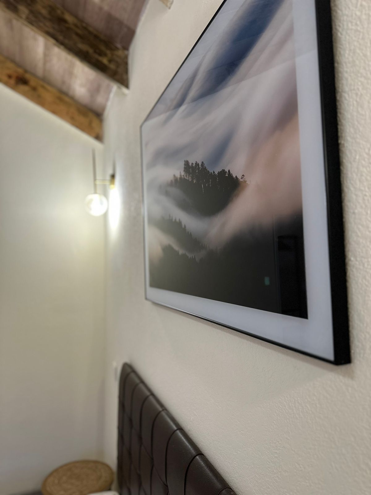 A framed landscape painting on a wall, a light fixture, and a textured wall.