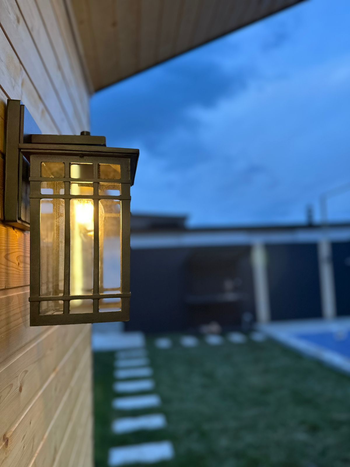 A wooden exterior wall with a black lantern-style light fixture.