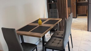 Een moderne eetruimte met een houten tafel, vier grijs gestoffeerde stoelen en een gele vaas.