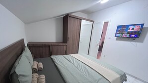 Een slaapkamer met een bed, een kledingkast, een televisie en een deur naar de badkamer.