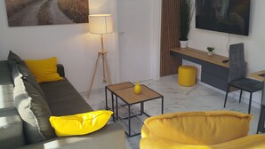 Een moderne woonkamer met een bank, een salontafel, een televisie en een schilderij aan de muur.
