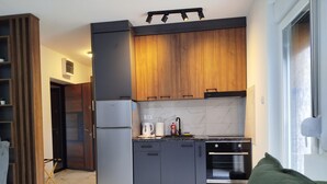 Een moderne keuken met donkere kastjes, een roestvrijstalen koelkast, een inbouwoven en een marmeren achterwand.