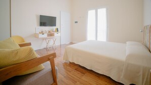 Un dormitorio con cama, escritorio, silla y televisor en la pared.