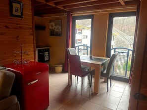 A cozy cabin interior with a dining area, a red refrigerator, and a view of the outside. - Dog-friendly House With Sauna, Bubble Bath (Bouillon)