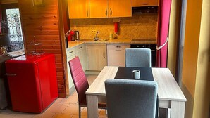 A compact kitchen with wooden cabinets, a red refrigerator, and a dining area with a table and chairs. - Dog-friendly House With Sauna, Bubble Bath (Bouillon)