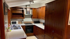 Une cuisine compacte dotée de meubles en bois, d’un four à micro-ondes, d’une cuisinière à gaz et d’un lave-vaisselle.