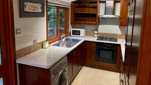 Une cuisine compacte équipée d’un lave-linge intégré, d’un four à micro-ondes et d’une cuisinière.