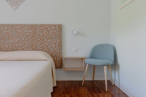 Une chambre à coucher comprenant un lit, une chaise, une table de chevet et un luminaire fixé au mur.