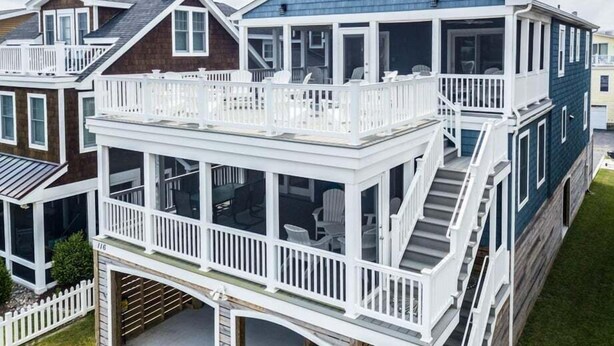 Una casa de dos pisos con un balcón, un porche cubierto y una escalera que conduce al nivel superior.
