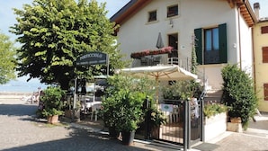 A building with a sign reading "PORTICCIOLO" and a balcony with outdoor seating. - Porticciolo del Campanello (Castelnuovo del Garda)