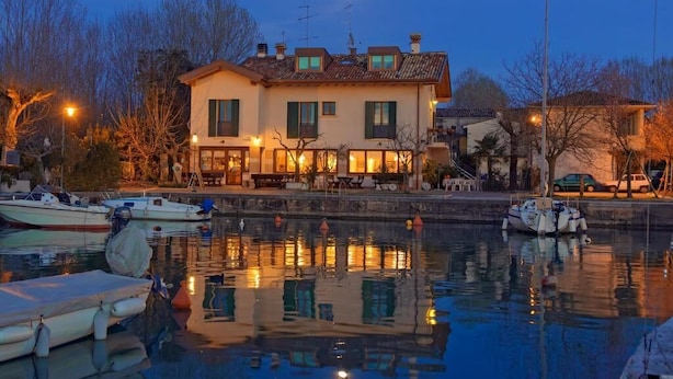 A waterfront property with a large house, a dock with boats, and a calm water body reflecting the lights. - Porticciolo del Campanello (Castelnuovo del Garda)