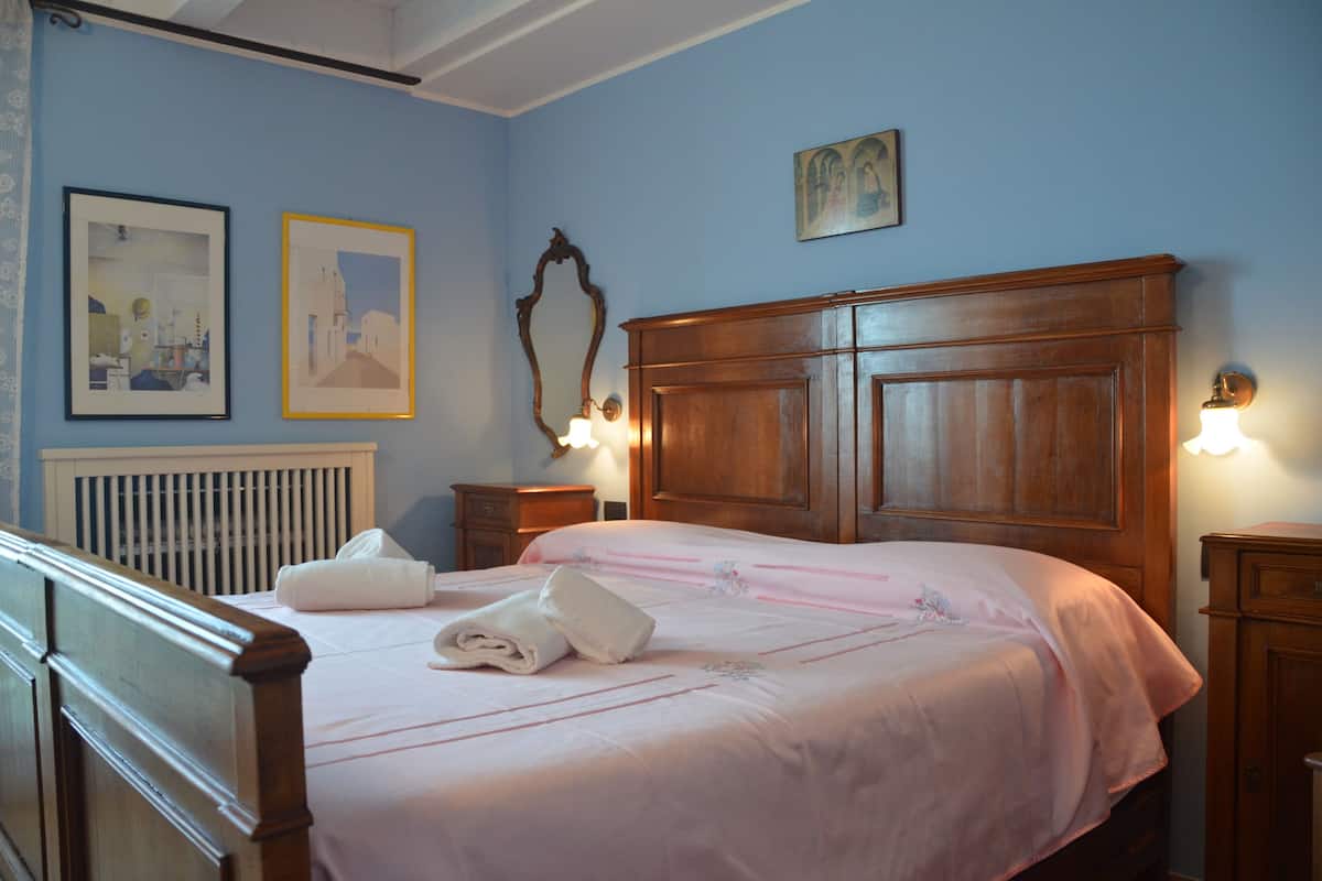 A neatly made bed with a wooden headboard, a nightstand with a lamp, and two framed pictures on the wall.
