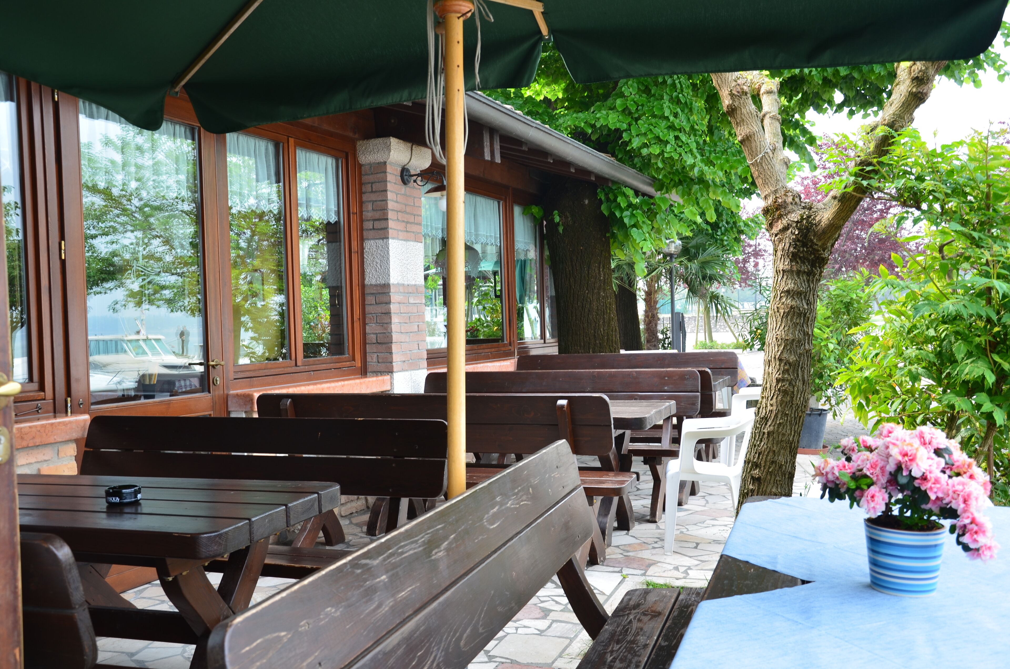 An outdoor seating area with wooden benches and tables, a potted plant, and a view of the street.