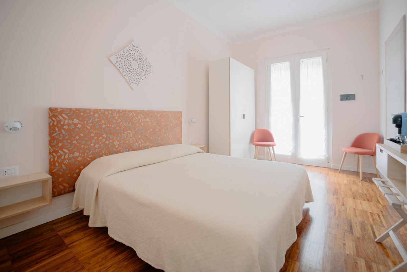 A bedroom with a bed, a desk, two chairs, and a wardrobe.