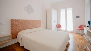 A bedroom with a bed, a desk, two chairs, and a wardrobe.