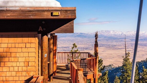 Een houten chalet met een balkon met uitzicht op een besneewd berglandschap.