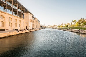 Ein Kanal mit einem modernen Gebäude an einer Seite und einer Stadtansicht im Hintergrund.