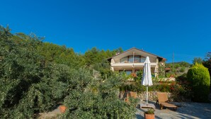 A two-story house with a balcony, surrounded by lush greenery and a clear blue sky. - 4-Bedroom Cappadocia Stone Villa in Charming Gökbel with Pool & Scenic Views (Gökbel)