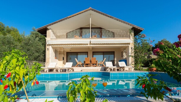 A two-story building with a balcony, a swimming pool, and outdoor seating. - 4-Bedroom Cappadocia Stone Villa in Charming Gökbel with Pool & Scenic Views (Gökbel)