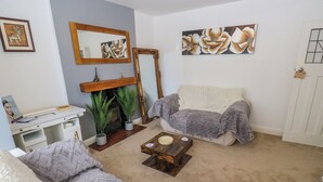 A living room with a sofa, a coffee table, a fireplace, a desk, and a mirror. - Middleton Park House (Leeds)