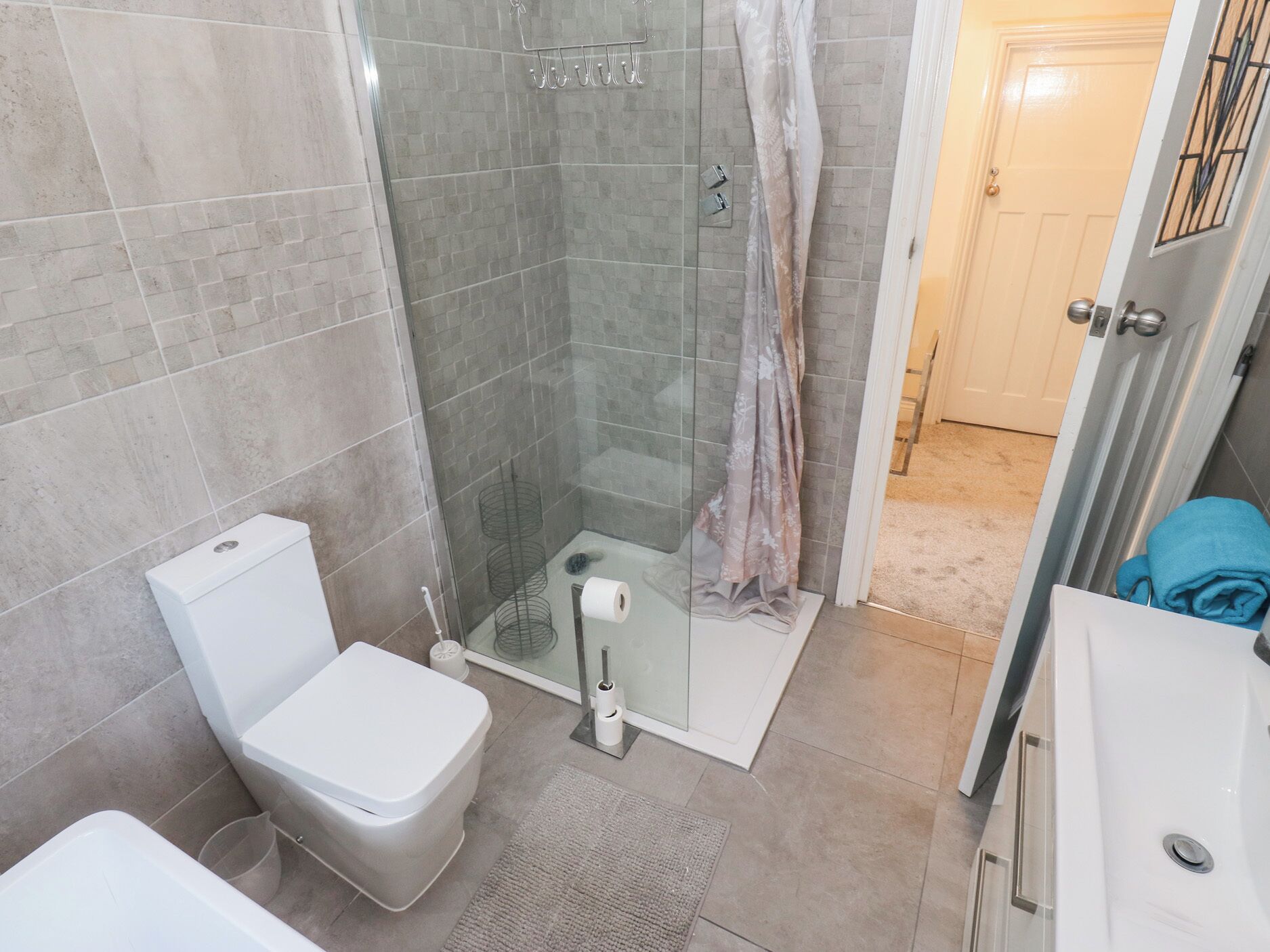 Een moderne badkamer met een glazen douchecabine, een toilet en een wastafel.