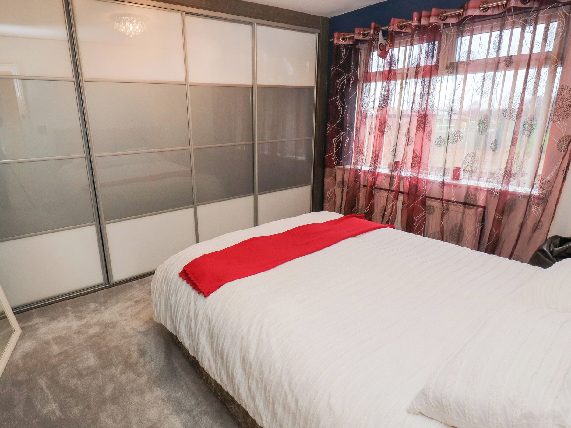Une chambre à coucher avec un lit, une porte coulissante et une fenêtre avec des rideaux.